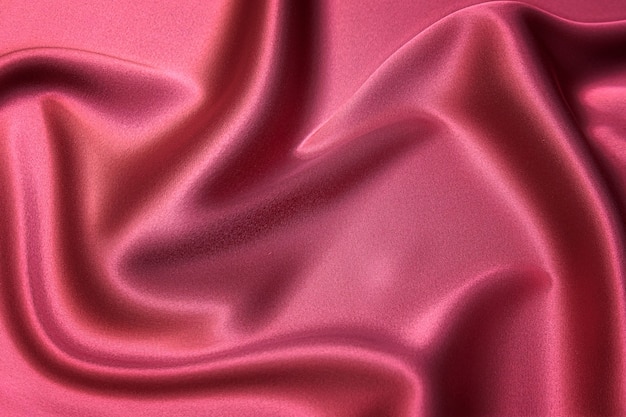 Close-up texture of natural red or pink fabric or cloth in same color. Fabric texture of natural cotton, silk or wool, or linen textile material. Red and orange canvas background.