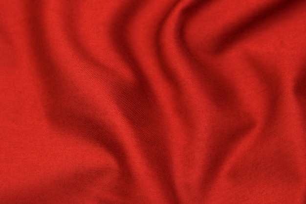 Close-up texture of natural red or pink fabric or cloth in same color. Fabric texture of natural cotton, silk or wool, or linen textile material. Red and orange canvas background.