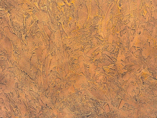 Close-up of textured plaster in golden colors. Modern interior design. Relief texture of putty.