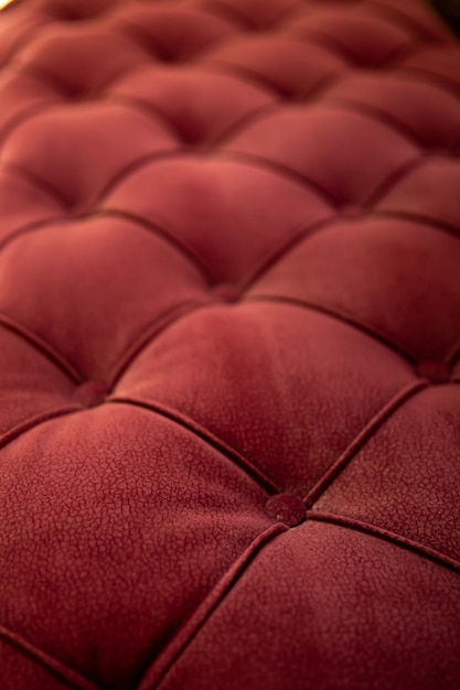 Close up textured red velvet fabric modern sofa with sunken buttons