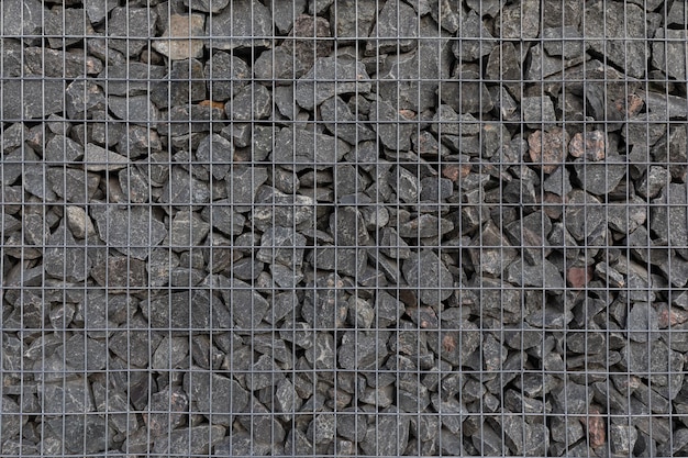 Foto close-up textuur van moderne privacy hek gemaakt van gabion gegalvaniseerd stalen rooster met granieten stenen