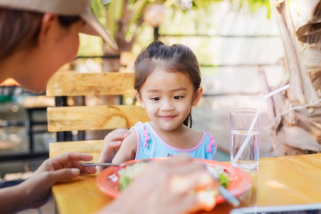 彼女の母親とレストランで食べるタイの子供を閉じます