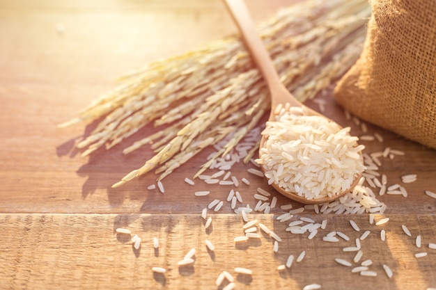 Photo close up thai jasmine rice in spoon and small sack on wooden table