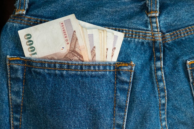Foto chiuda sulle banconote della tailandia in tasca dei jeans