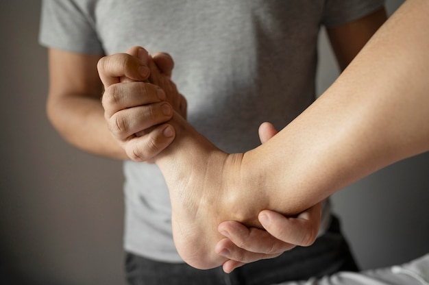 Photo close-up therapist holding patient foot