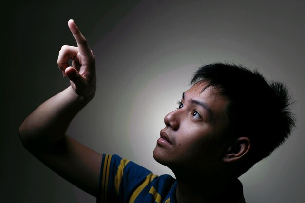 Photo close-up of thoughtful boy gesturing against gray background