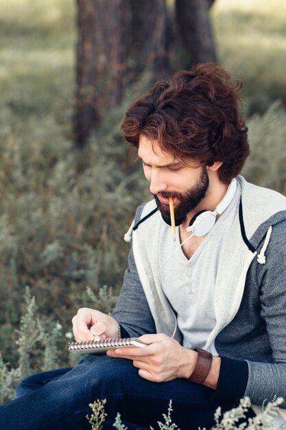 Close-up of thoughtful man with notebook biting pencil.