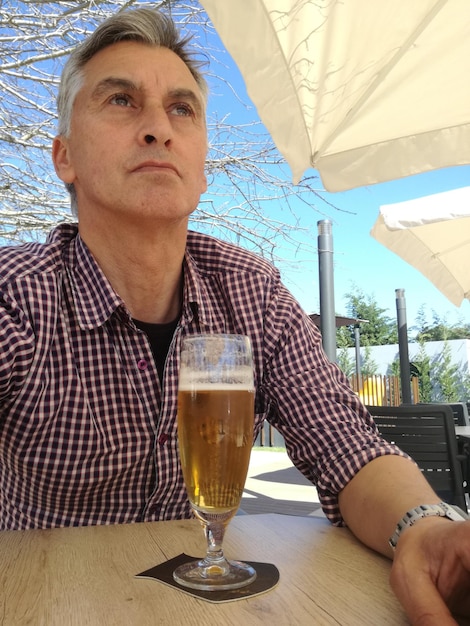 Photo close-up of thoughtful mature man having beer at outdoor restaurant