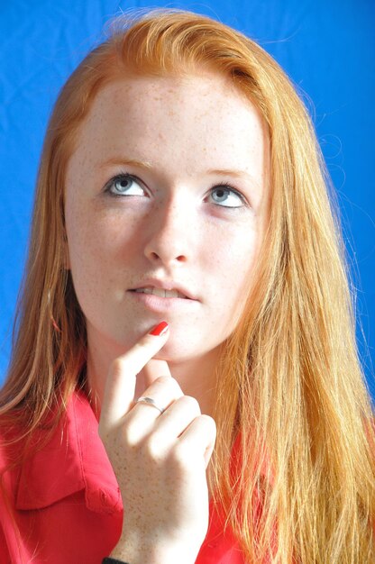 Close-up of thoughtful teenage girl against blue background