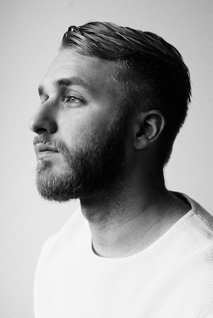 Close-up of thoughtful young man with beard against white background