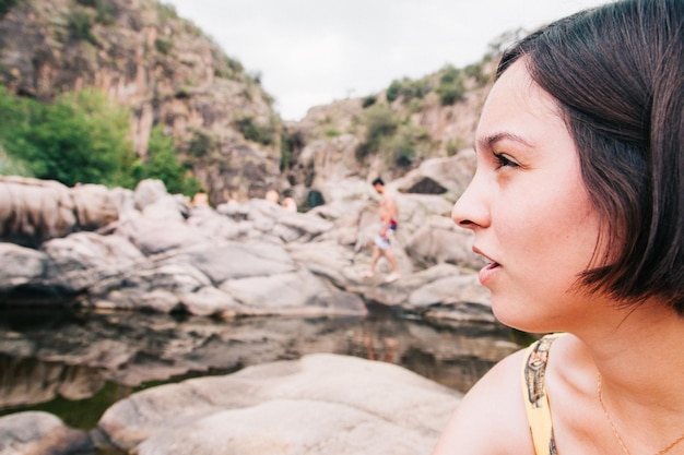 Foto close-up di una giovane donna pensierosa che guarda lontano contro le formazioni rocciose