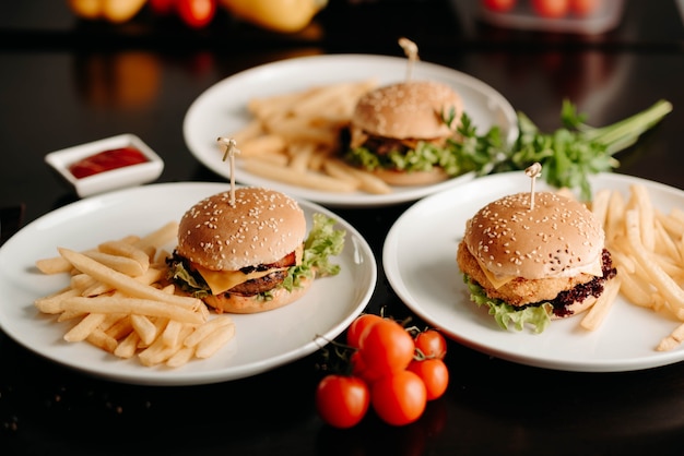 Photo close-up, three different burgers with fries on the table in the restaurant