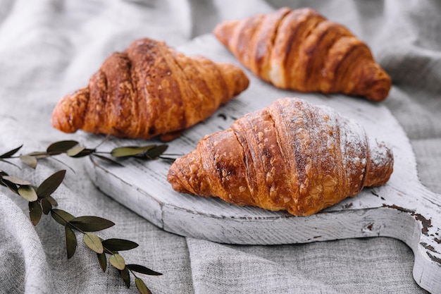 Close up three freshly baked croissants with sugar powder on a wooden desk