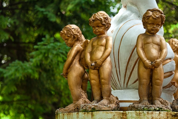 도시 공원에서 분수에 청동 스탠드로 덮여 세 작은 천사 소년 동상의 근접