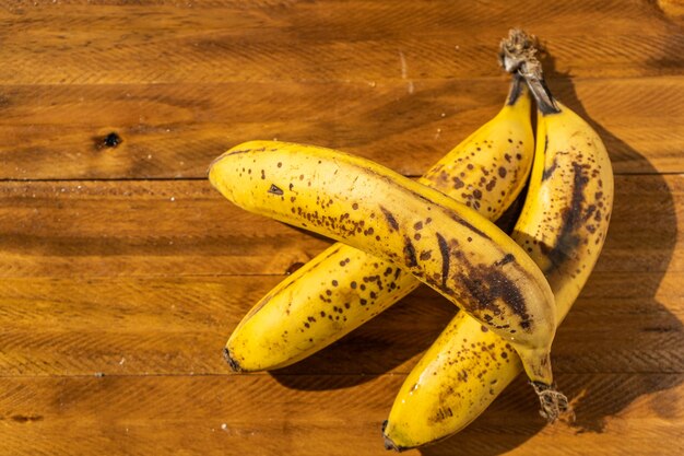 Крупный план трех спелых бананов на деревянной доске. Тропические и полезные фрукты.