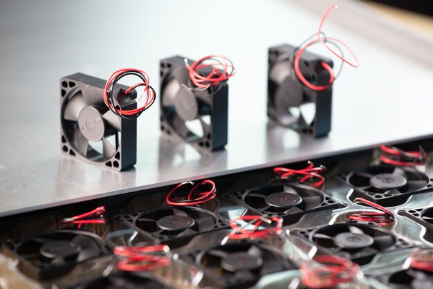 Close-up of three small computer coolers with wires lying on a table on a gray