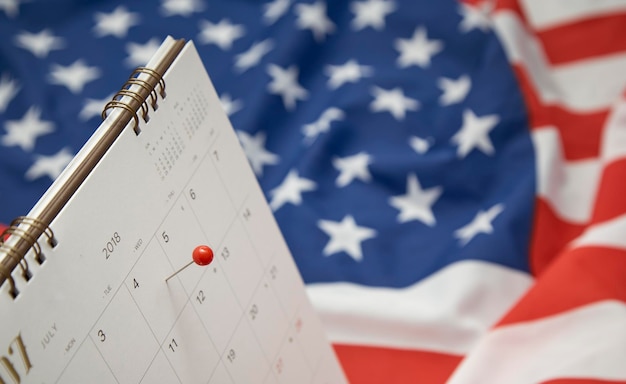 Photo close-up of thumbtack over calendar marking american national holiday