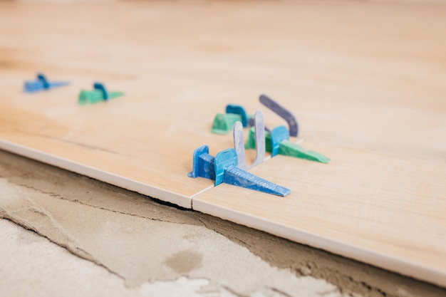 Close up tile leveling system on the floor. Plastic clips for bonding tiles