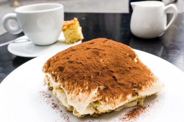 close-up of tiramisu in plate by coffee cup on table