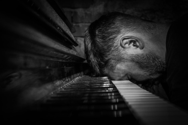 Foto close-up di un pianista stanco appoggiato al pianoforte