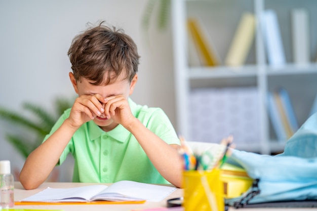 Close up on tired schoolboy rubbing his eyes