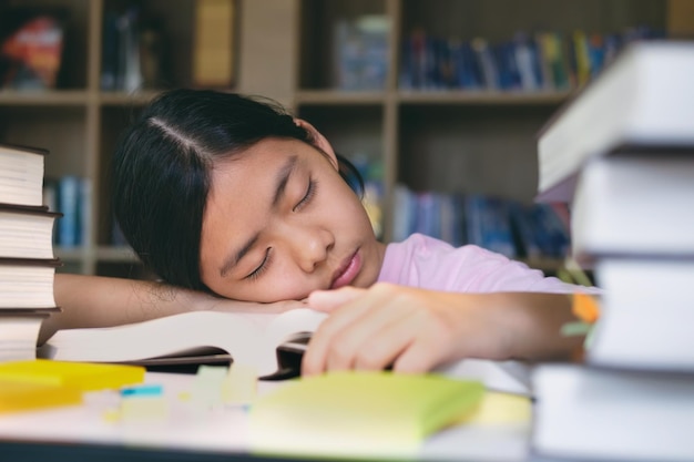 Close-up of tired teenage girl with books sleeping on table