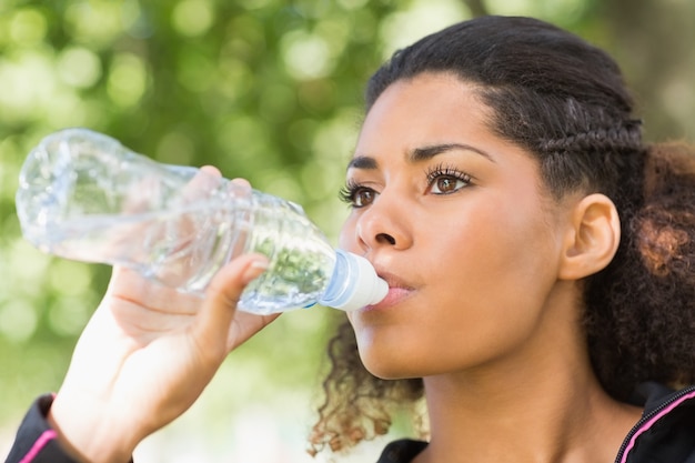 Close up of a tired woman drinking water in park