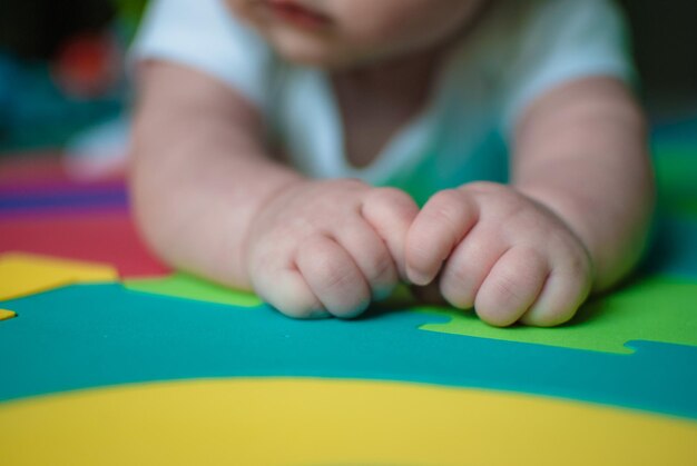 Photo close-up of toddler lying on multi colored sheet