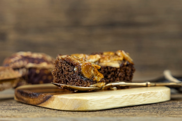 Close up toffee cake on steel spoon and on wooden wall.