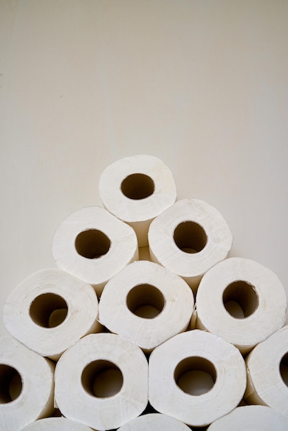 Photo close up toilet paper rolls on a wooden shelf in a bathroom.