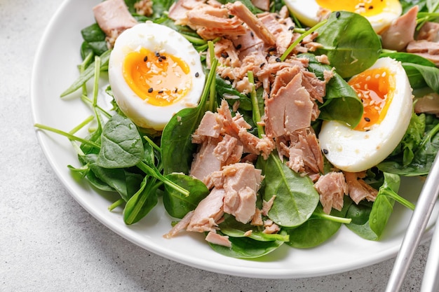 Close-up Tonijnsalade met gekookt ei en spinazie op witte plaat Keto dieet gezond voedsel Fresh