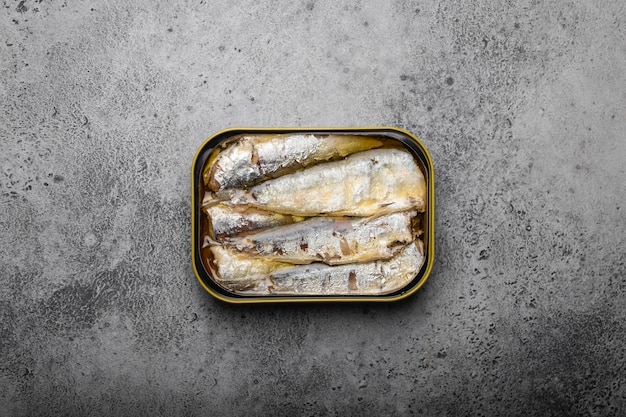 Close up and top view of canned sardine in a tin over gray rustic concrete background. Tinned fish as a convenient, fast, healthy food and source of omega-3 fatty acids, protein and vitamin D