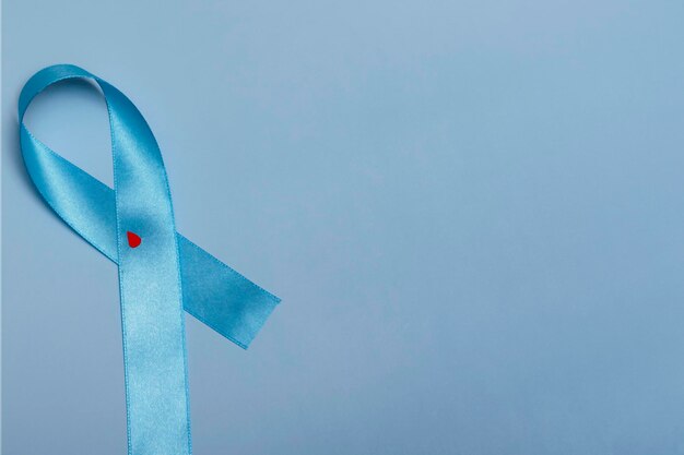 Close up top view of concept for World Diabetes Day 14 November. Blue ribbon with drops of blood on a blue background.