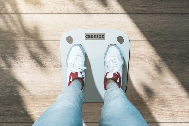 Close up and top view of creative casual dressed feet on scales asking for help Lose weight and measuring concept Wooden parquet floor background with shadows