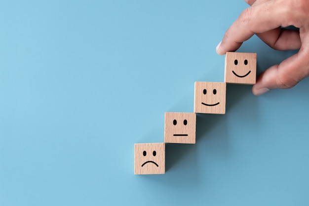 Foto chiudere la mano del cliente vista dall'alto scegliere faccina sorridente sul cubo di legno