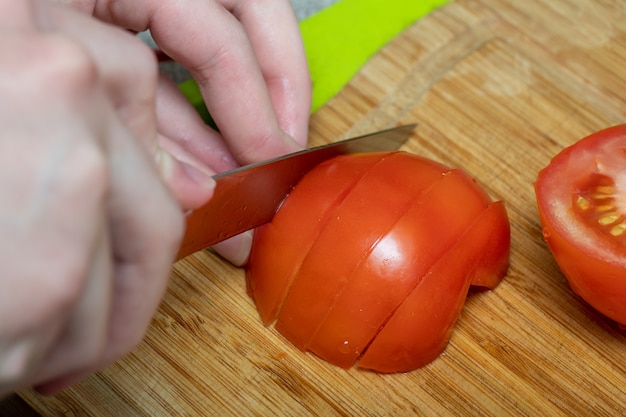 Close-up top view female hands cut tomato for making salad. Healthy and Eating Concept.