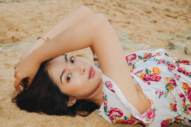 Close up top view of a smiling woman lying and relaxing on beach sand