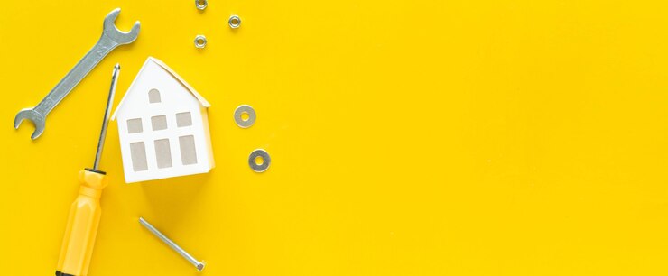 close up top view on white color of model house with metal wrench and instrument on yellow wallpaper