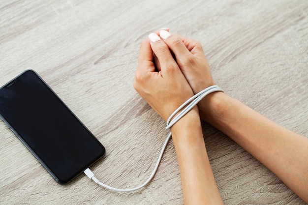 Close up top view of woman hands connected with wire cable to smartphone gadget.