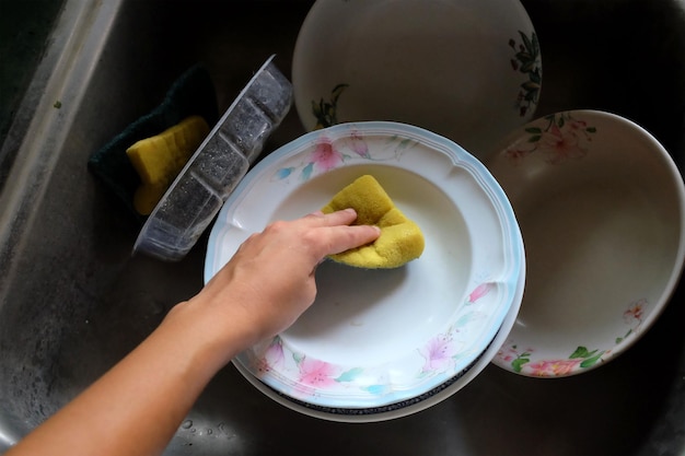 Visto da vicino e dall'alto donna lavando il piatto nel lavandino cucina moderna