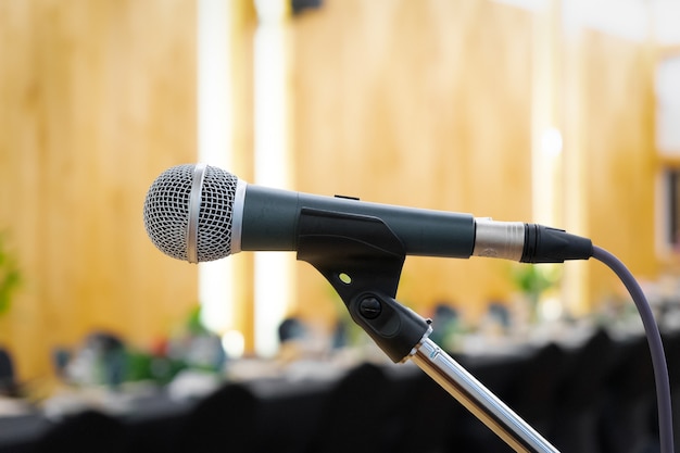 Close-up tot microfoon naast het podium met vervagen lange zwarte tafel etenstijd in wolfraam warm licht.