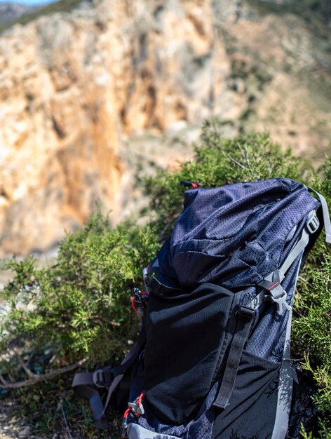 Foto chiuda sullo zaino turistico sulla scogliera nel concetto della foto della valle della montagna