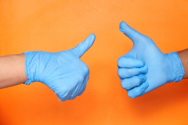 Photo close-up of a tow people hand in medical gloves showing a thumb-up.