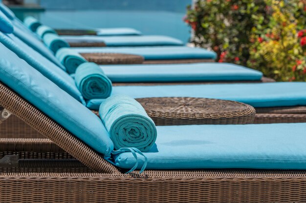 Close up of towels on lounge chairs near a luxury swimming pool at a tropical resort spa in island Zanzibar, Tanzania, East Africa