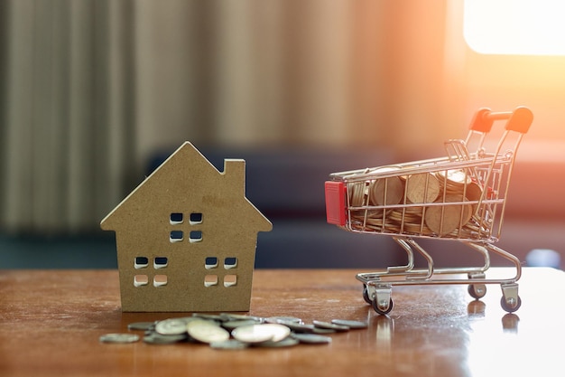 Photo close up of toy house by shopping cart with coins