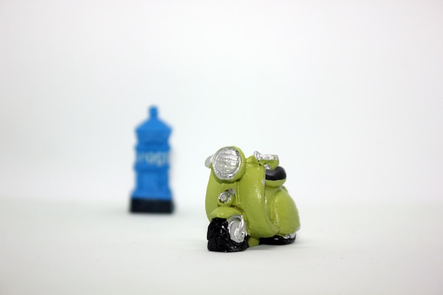 Photo close-up of toy motor scooter against public mailbox over white background