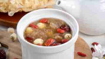 Photo close up of traditional chinese sweet snow white fungus soup with lotus seed red dates jujube and wolfberry goji berry gojiberry on white background