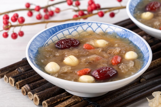 Close up of traditional Chinese sweet snow white fungus soup with lotus seed red dates jujube and wolfberry goji berry gojiberry on white background