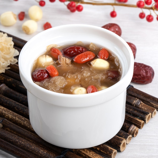 Close up of traditional Chinese sweet snow white fungus soup with lotus seed red dates jujube and wolfberry goji gojiberry on white background