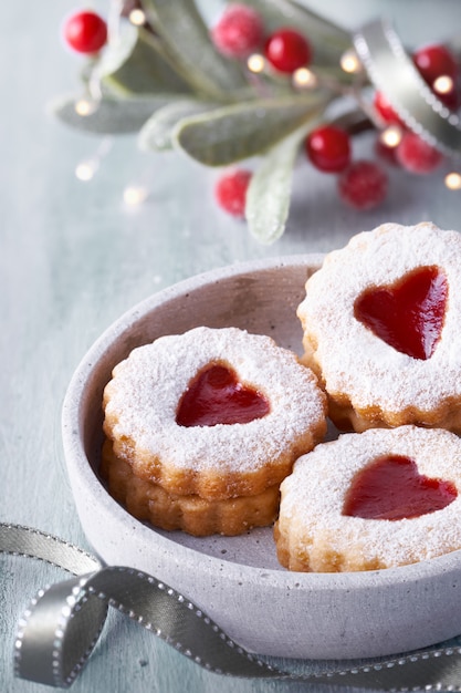 Close-up on traditional Christmas Linzer jam cookies on white table with Xmas decorations